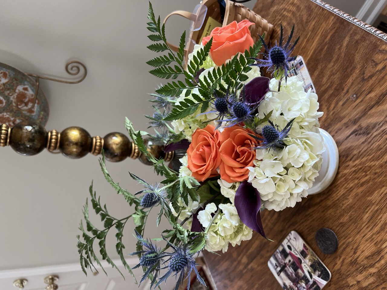 Arrangement with orange roses, sea holly, and hydrangea